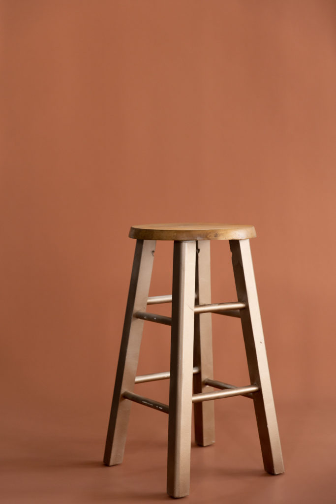 wooden stool in front of a henna seamless paper backdrop at wv photography studio
