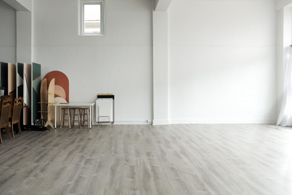 an open natural light space for photography in the 304 collective studio in fairmont wv with white walls a beutral gray floor and a collection of backdrops