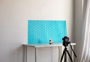 a camera set up to take product photos in front of bright blue textured backdrop