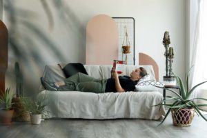 a woman reclined on a couch in a photography studio, reading a book